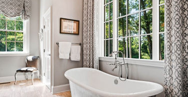 Monochromatic Bathroom with White and Gray Freestanding Tub Under Window